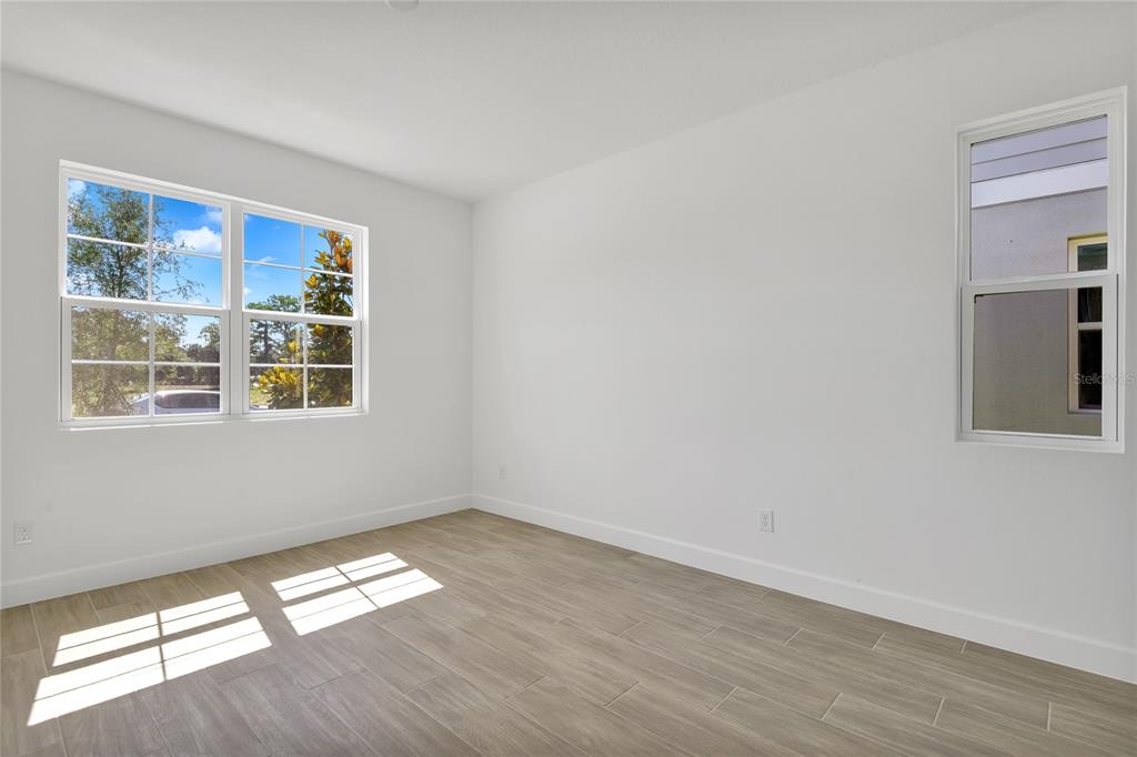 A bedroom with gray carpet, white walls, a closet, and an attached bathroom — 141 WATERSTONE LOOP, TAVARES, FL