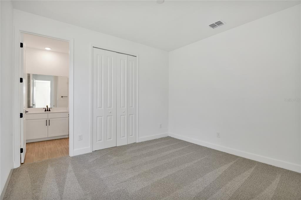A bathroom features a white vanity, a black faucet, a toilet, and a glass-enclosed shower — 141 WATERSTONE LOOP, TAVARES, FL