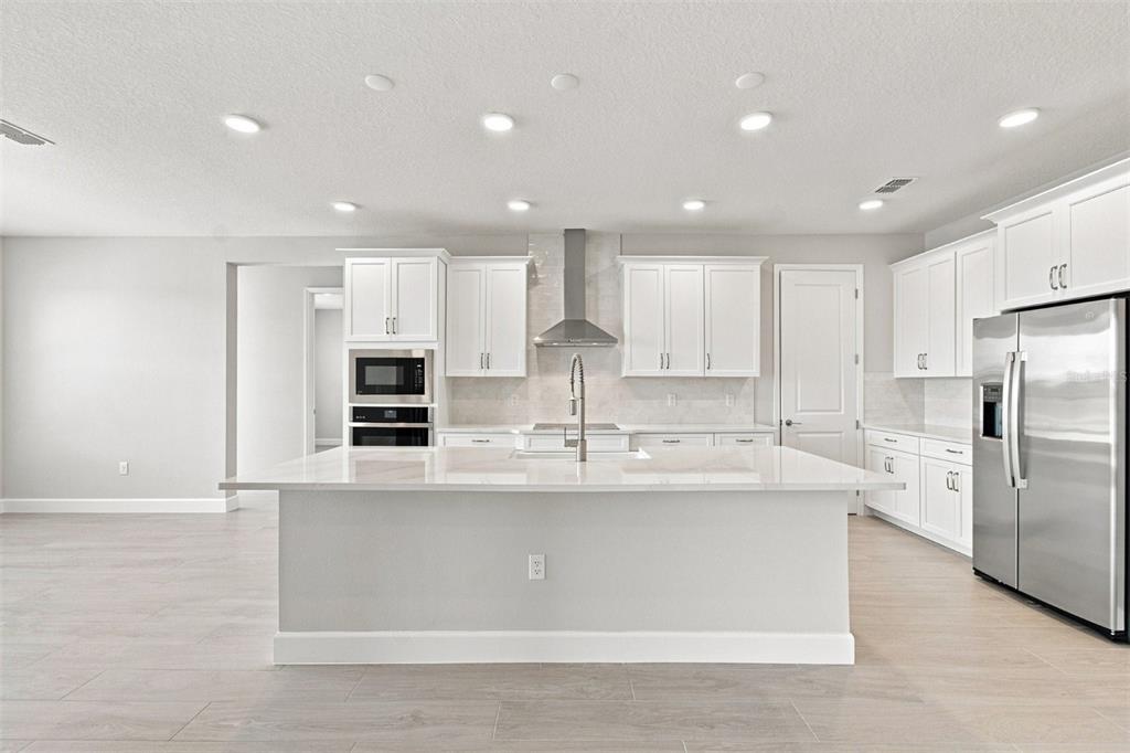 An unfinished room features a central kitchen island, recessed lighting, and protective floor paper — 17036 OVERSTORY ROAD, ORLANDO, FL
