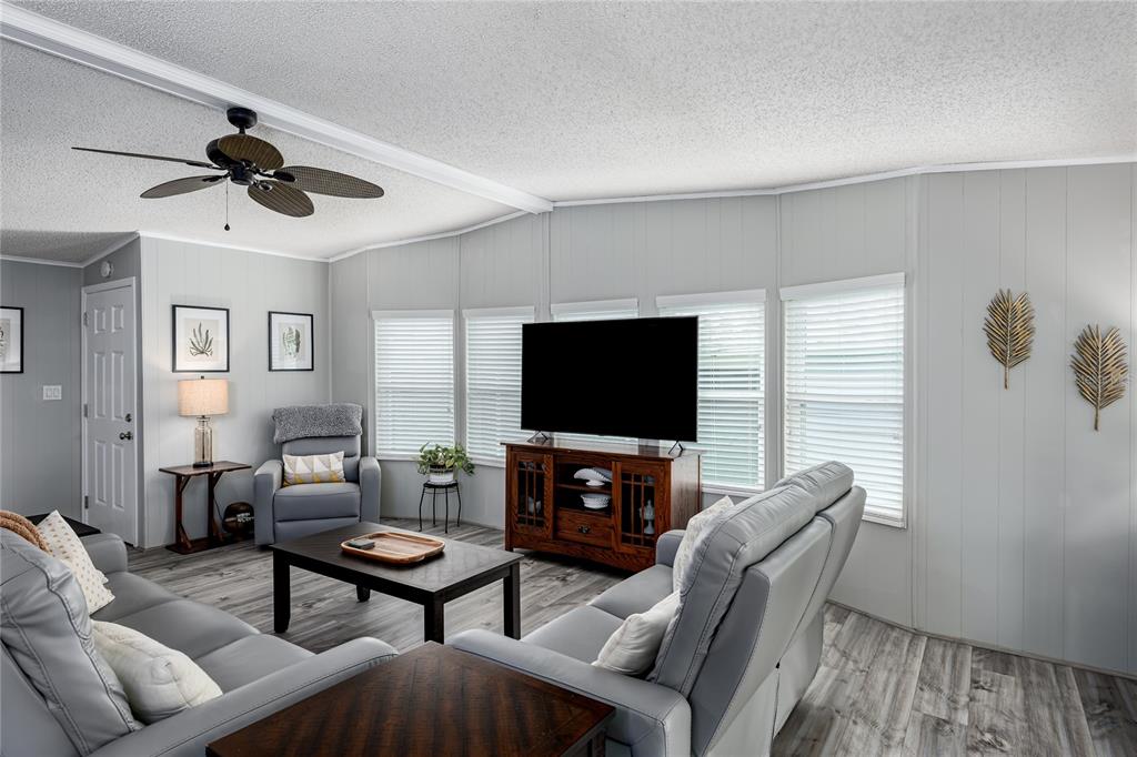 A living room features gray walls, wood-look flooring, a ceiling fan, and a television console — 158 OSPREY CIRCLE, ELLENTON, FL