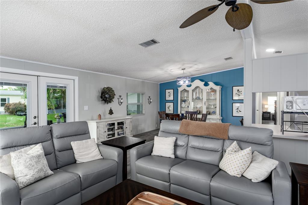 A living room with gray leather sofas, a blue accent wall, and a dining area — 158 OSPREY CIRCLE, ELLENTON, FL