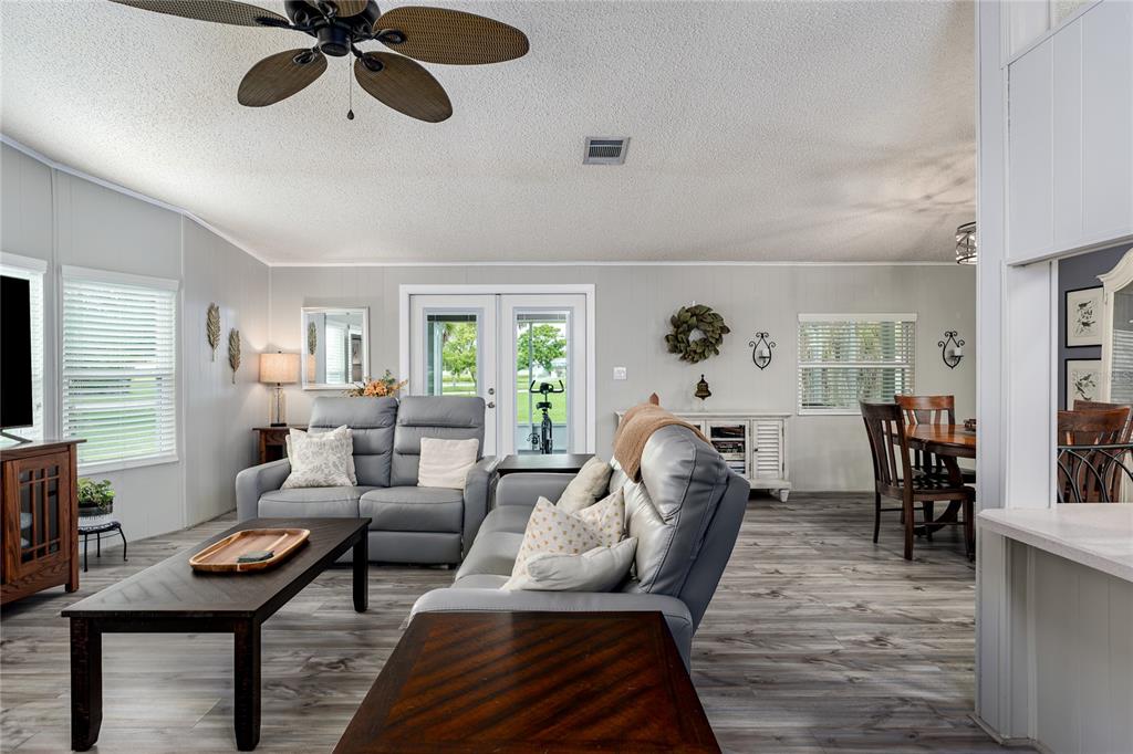 A living room with gray leather furniture, wood-look flooring, and a ceiling fan — 158 OSPREY CIRCLE, ELLENTON, FL