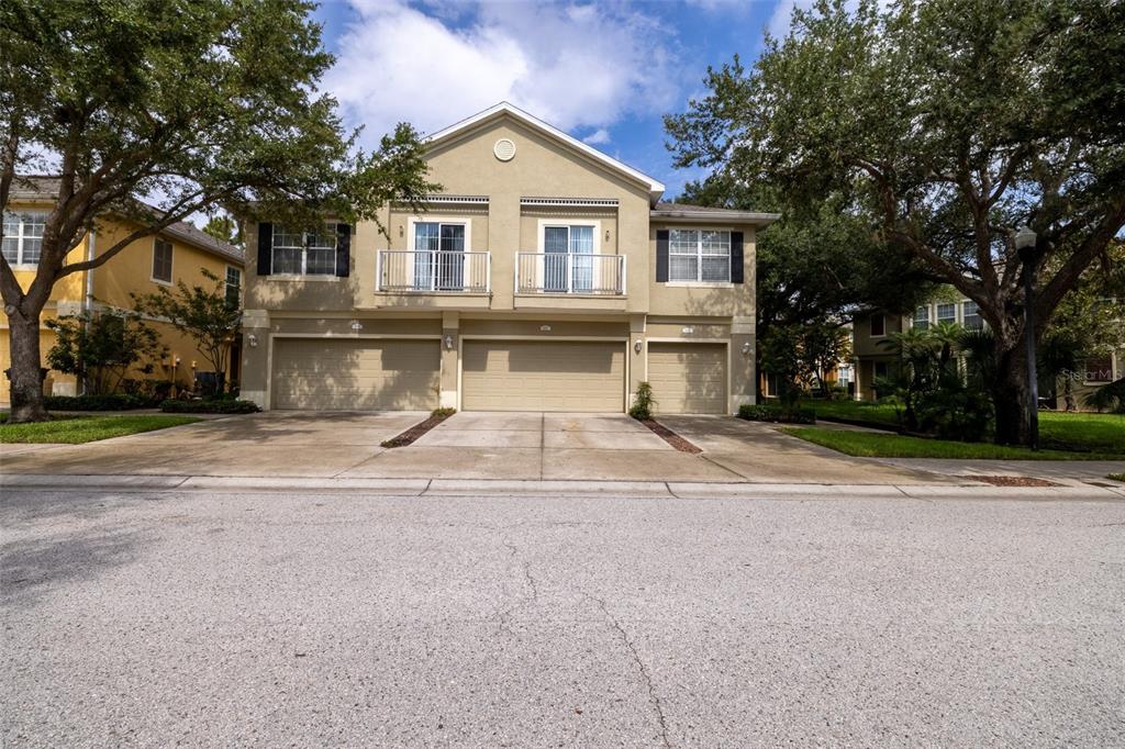 A two-story tan townhouse with three garage doors and two upper-level balconies — 6717 EAGLE FEATHER DRIVE, RIVERVIEW, FL