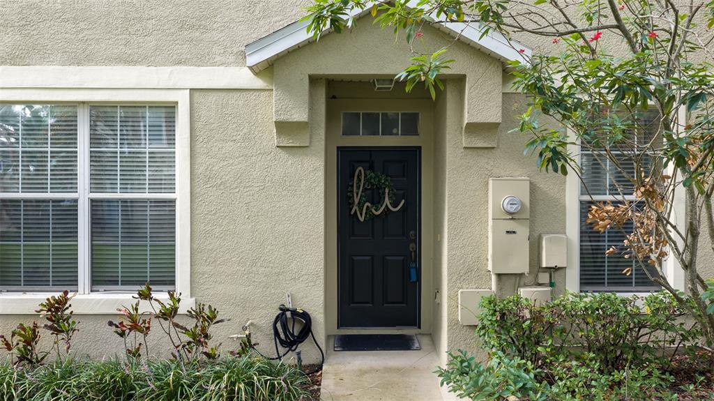 A tan stucco building exterior features a black front door with a wreath and windows — 6717 EAGLE FEATHER DRIVE, RIVERVIEW, FL
