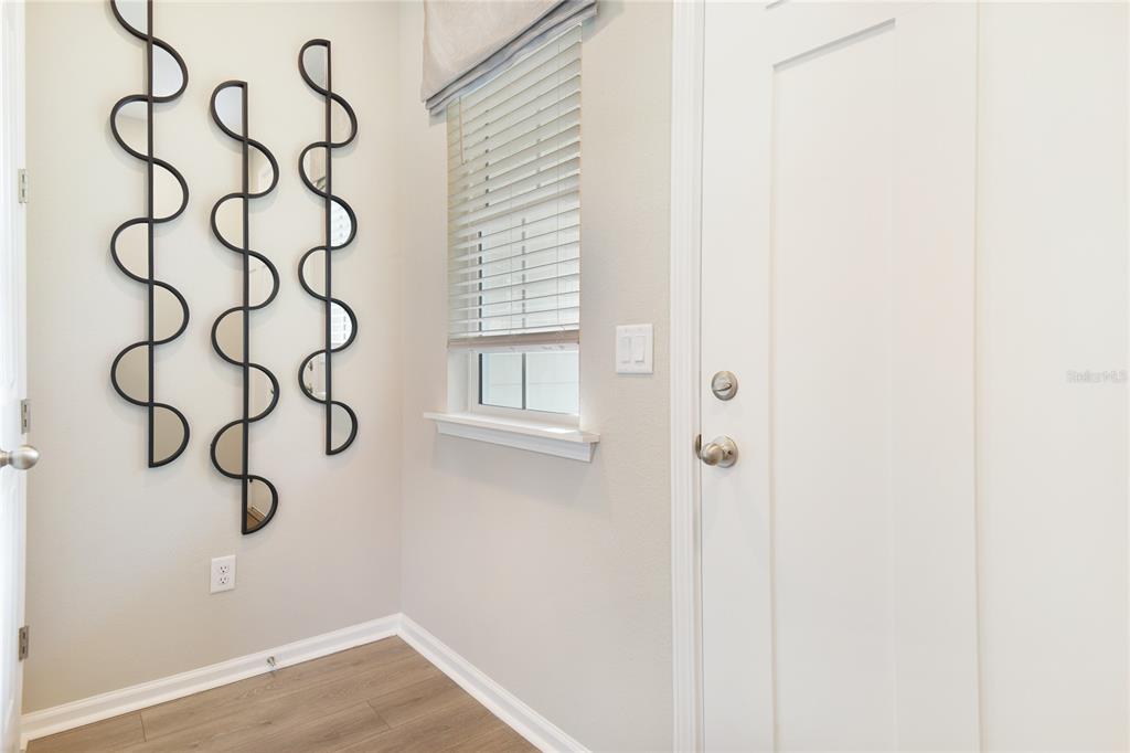 A room with light wood-look flooring, a window with blinds, and decorative metal wall art — 761 LAKE DELL AVENUE, DUNDEE, FL