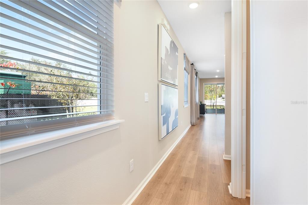 A hallway with wood-look flooring, two wall art pieces, and a window with blinds — 761 LAKE DELL AVENUE, DUNDEE, FL