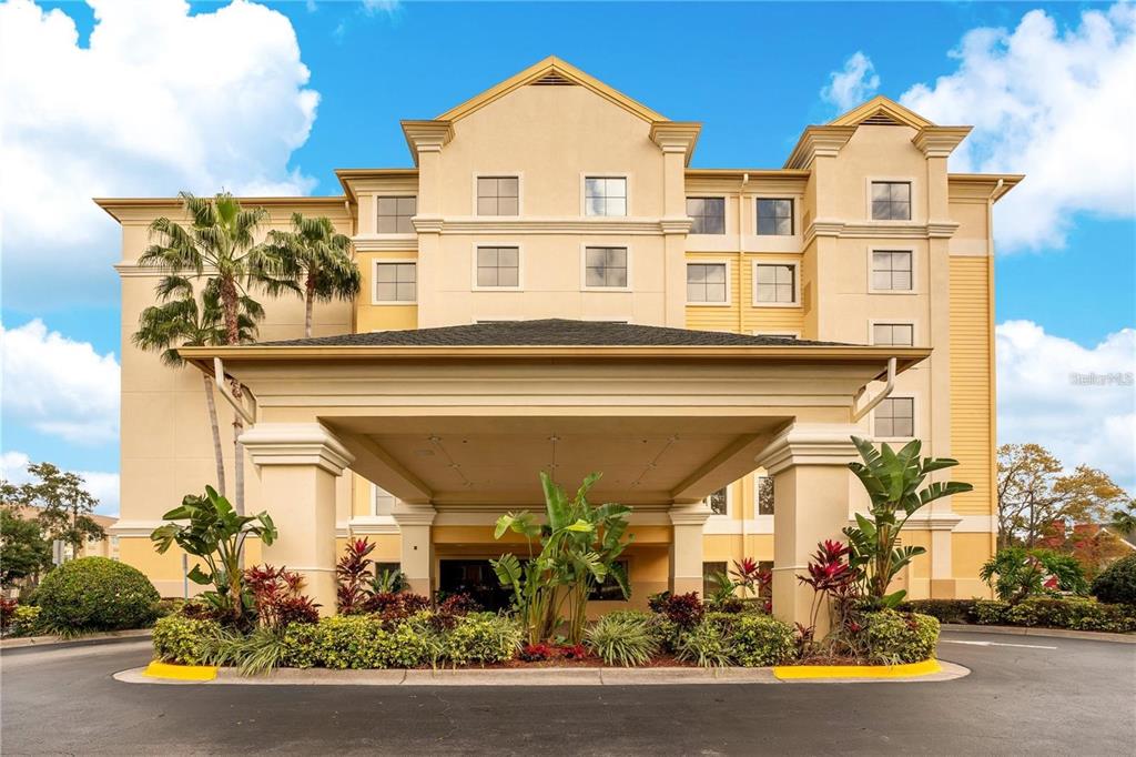 A multi-story hotel building features a large covered entrance with a driveway and landscaped gardens — 7601 CANADA AVENUE UNIT 630, ORLANDO, FL