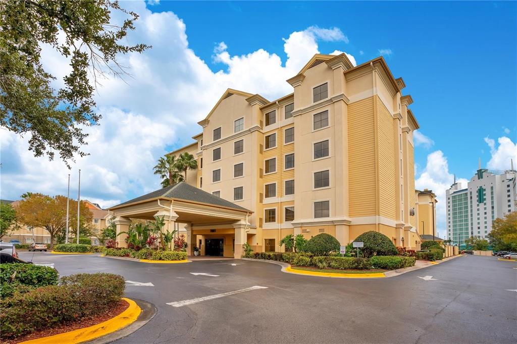 A multi-story hotel building features a covered entrance, yellow exterior walls, and a paved driveway — 7601 CANADA AVENUE UNIT 630, ORLANDO, FL