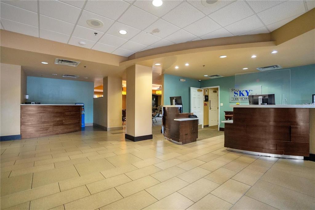 A hotel lobby features a tiled floor, two wooden reception desks, and light blue walls — 7601 CANADA AVENUE UNIT 630, ORLANDO, FL