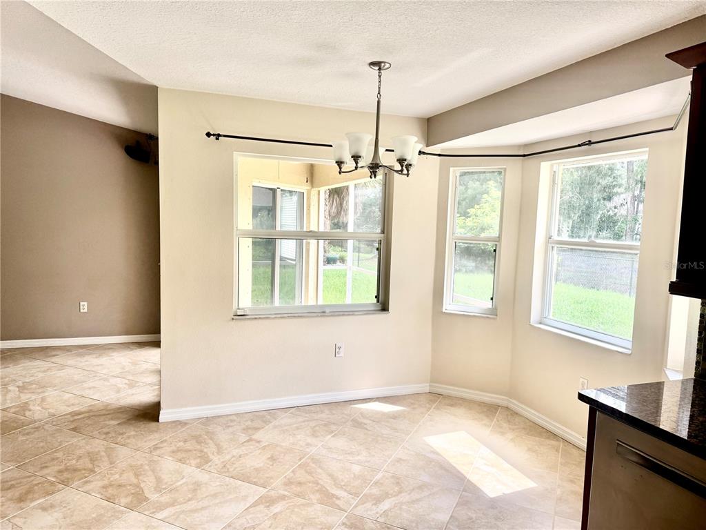 A dining area features tile flooring, a chandelier, and windows looking out to a patio — 2043 OLD TRENTON LANE, SARASOTA, FL