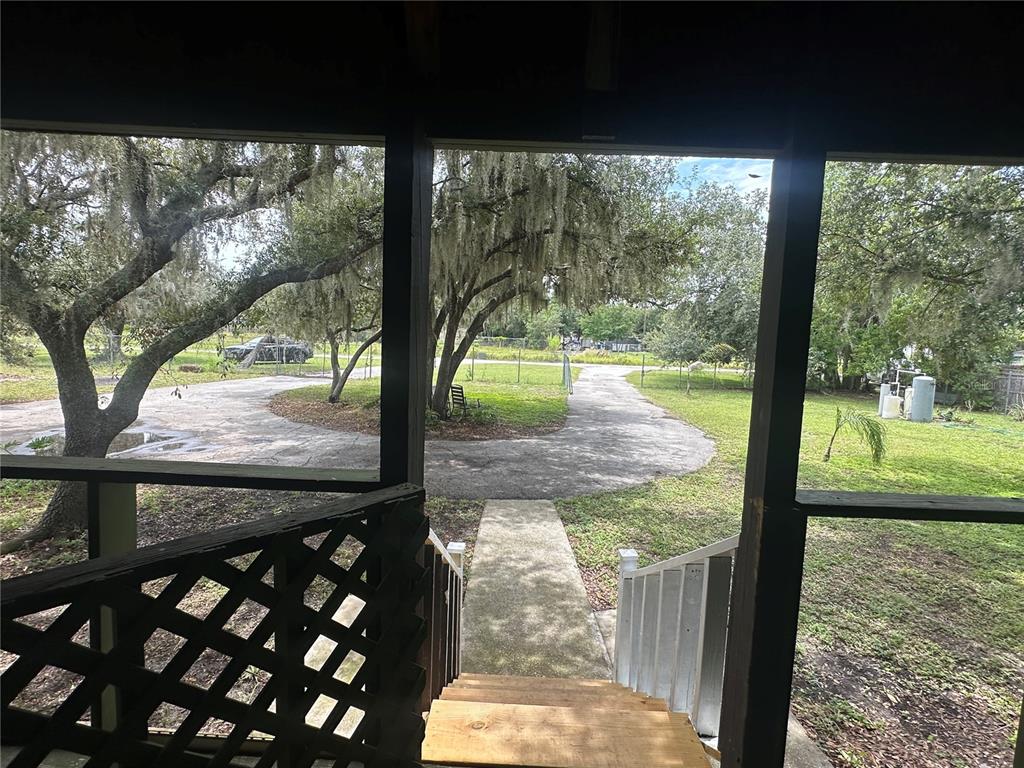 A view from a screened-in porch looking out onto a concrete driveway and trees — 2363 GERBER DAIRY ROAD, WINTER HAVEN, FL