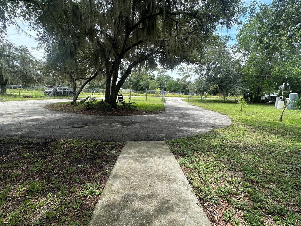 A concrete walkway leads to a circular driveway shaded by a large oak tree — 2363 GERBER DAIRY ROAD, WINTER HAVEN, FL