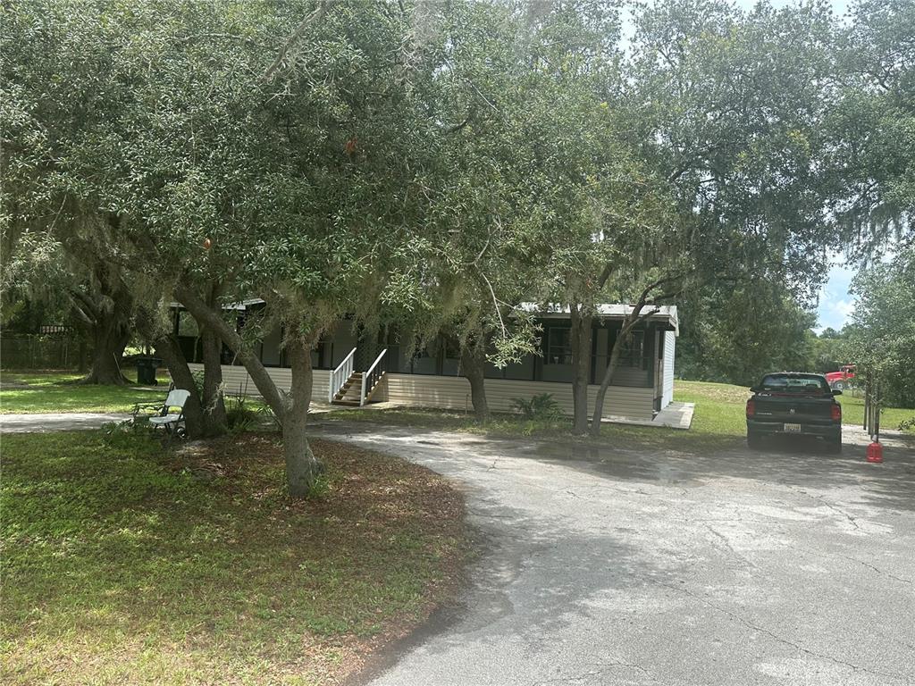 A single-story manufactured home sits on a wooded lot with a paved driveway — 2363 GERBER DAIRY ROAD, WINTER HAVEN, FL