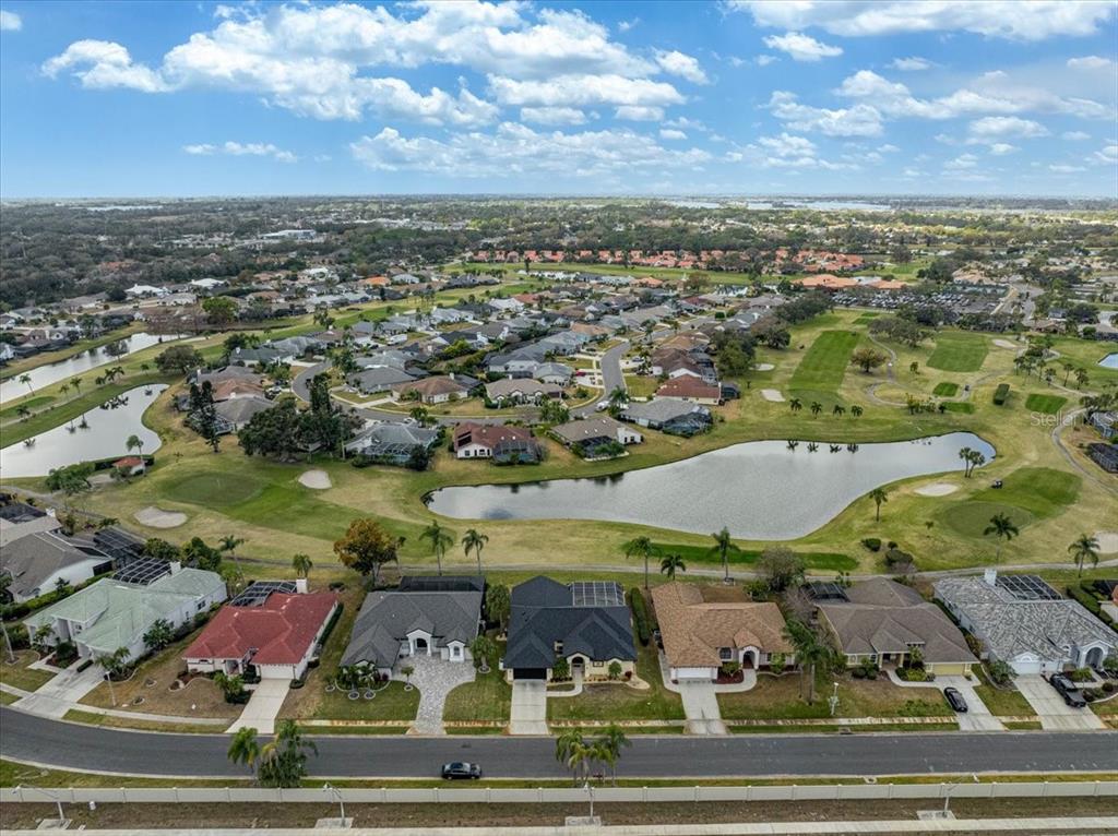 An aerial view shows a suburban neighborhood with houses bordering a golf course and pond — 5072 KILTY COURT E, BRADENTON, FL