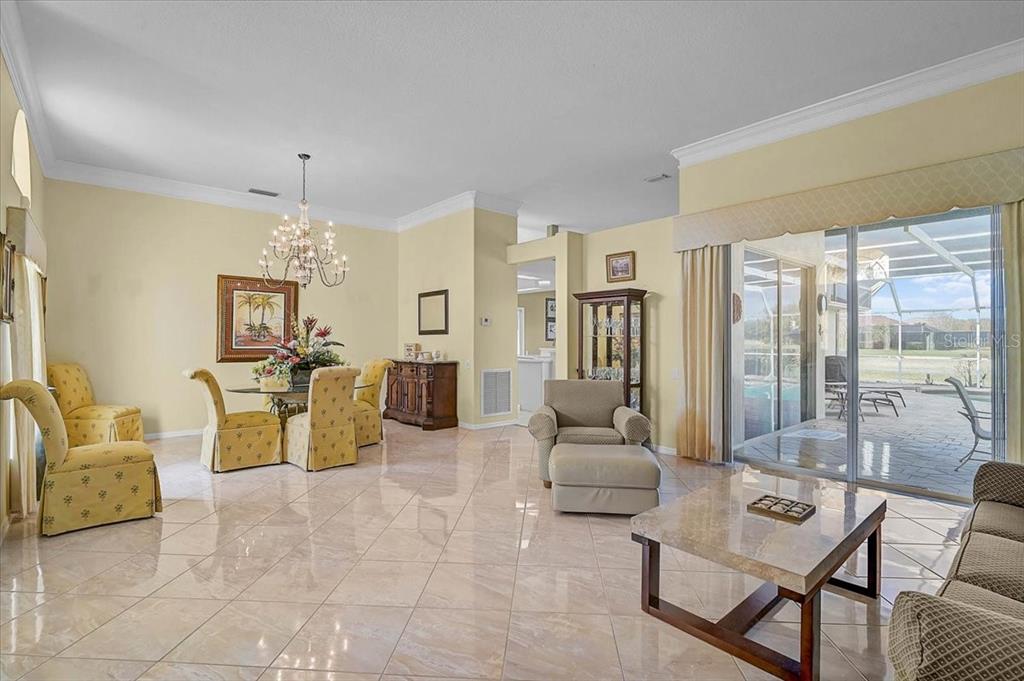 A spacious living and dining area with tile flooring, a chandelier, and sliding glass doors — 5072 KILTY COURT E, BRADENTON, FL