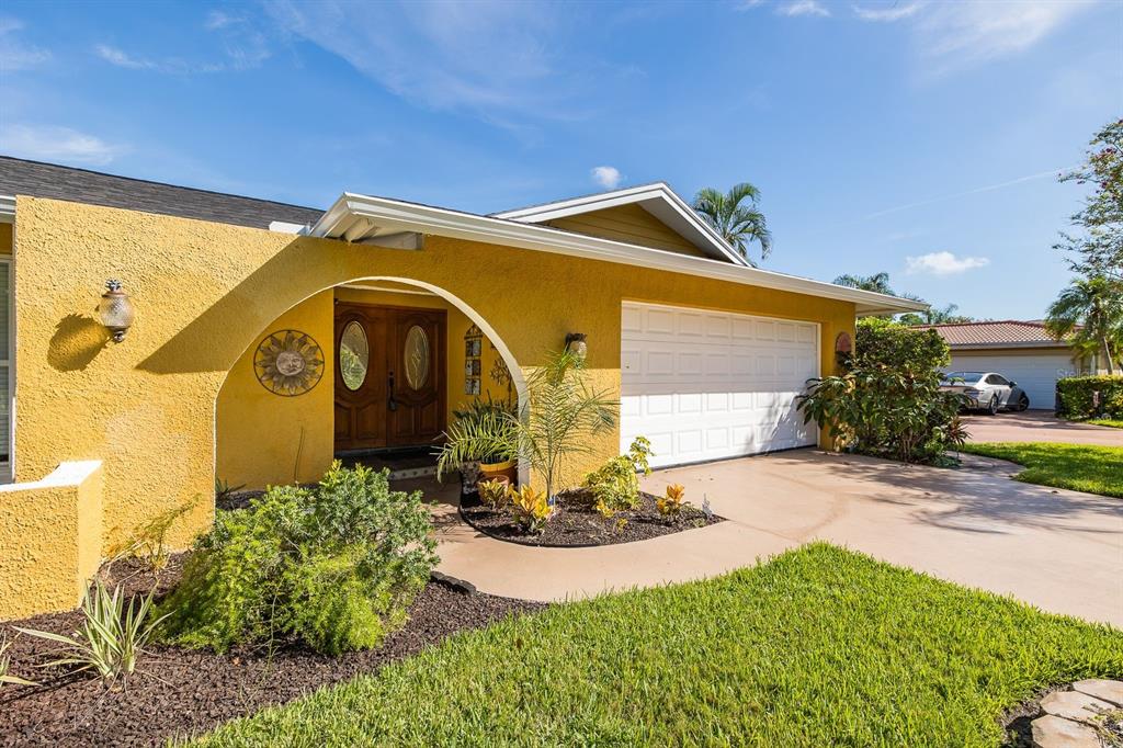 A yellow stucco house features a curved entryway, double wooden doors, and a white garage — 11555 PINE STREET, SEMINOLE, FL