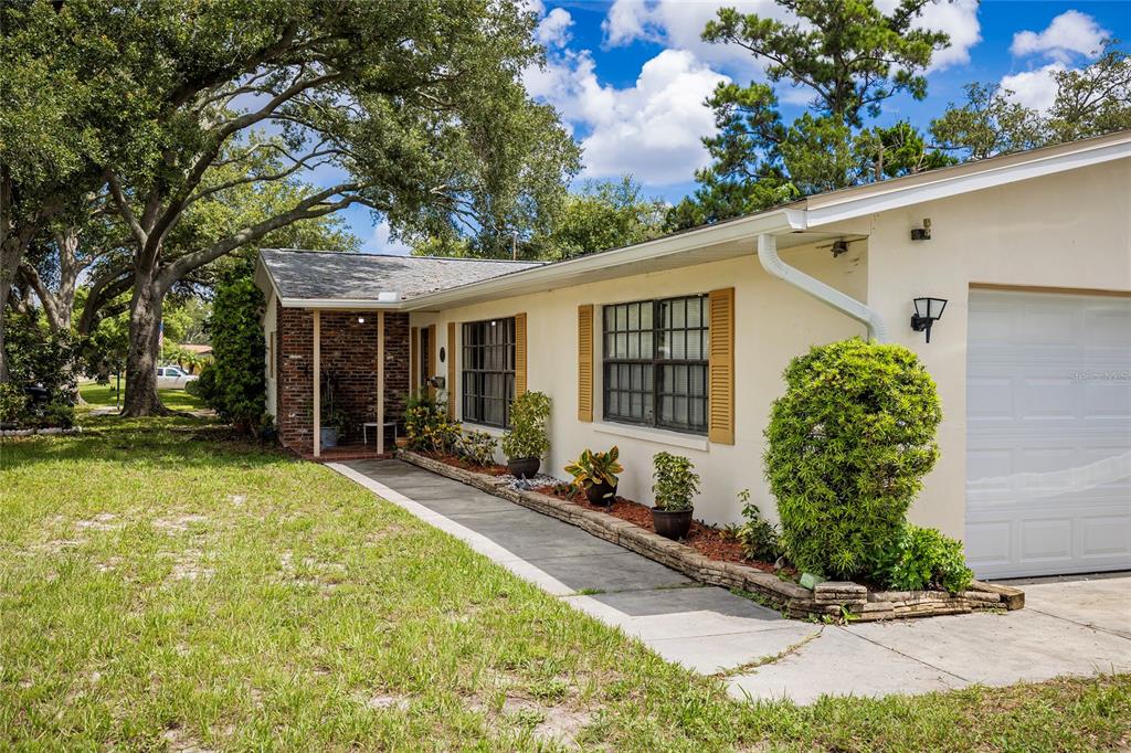 A single-story house with a brick entryway, light-colored stucco walls, and a white garage door — 1901 STANCEL DRIVE, CLEARWATER, FL