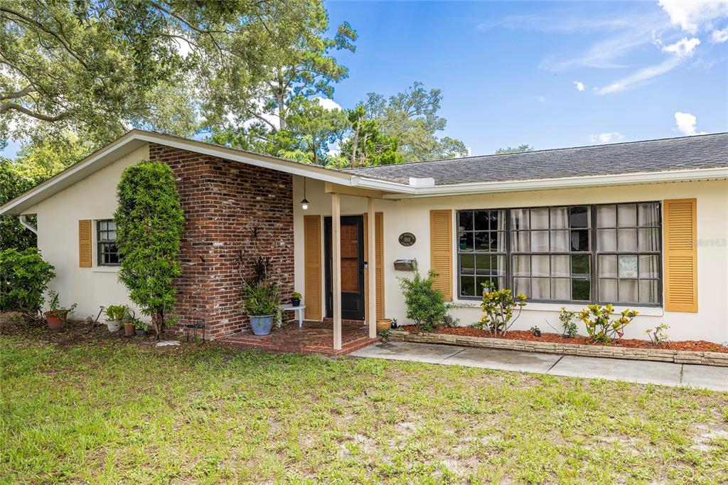 A single-story house features a brick facade, a covered entryway, and a large front window — 1901 STANCEL DRIVE, CLEARWATER, FL