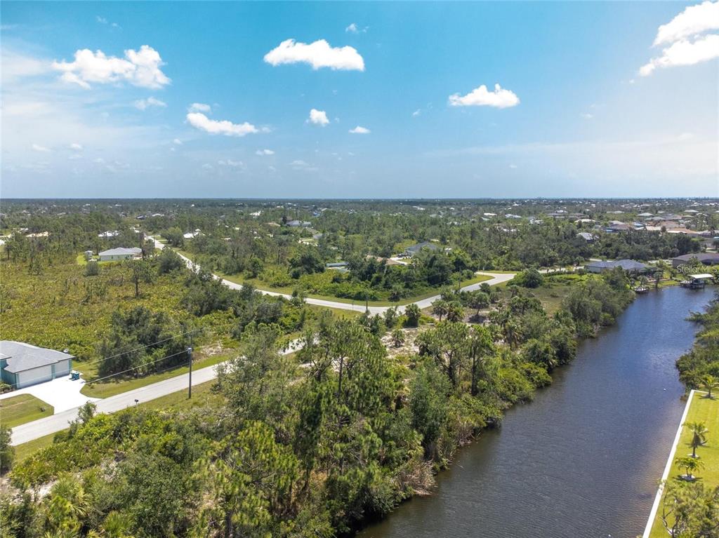 An aerial view shows a vacant residential lot outlined in red along a canal — 9602 GAZANIA DRIVE, PORT CHARLOTTE, FL