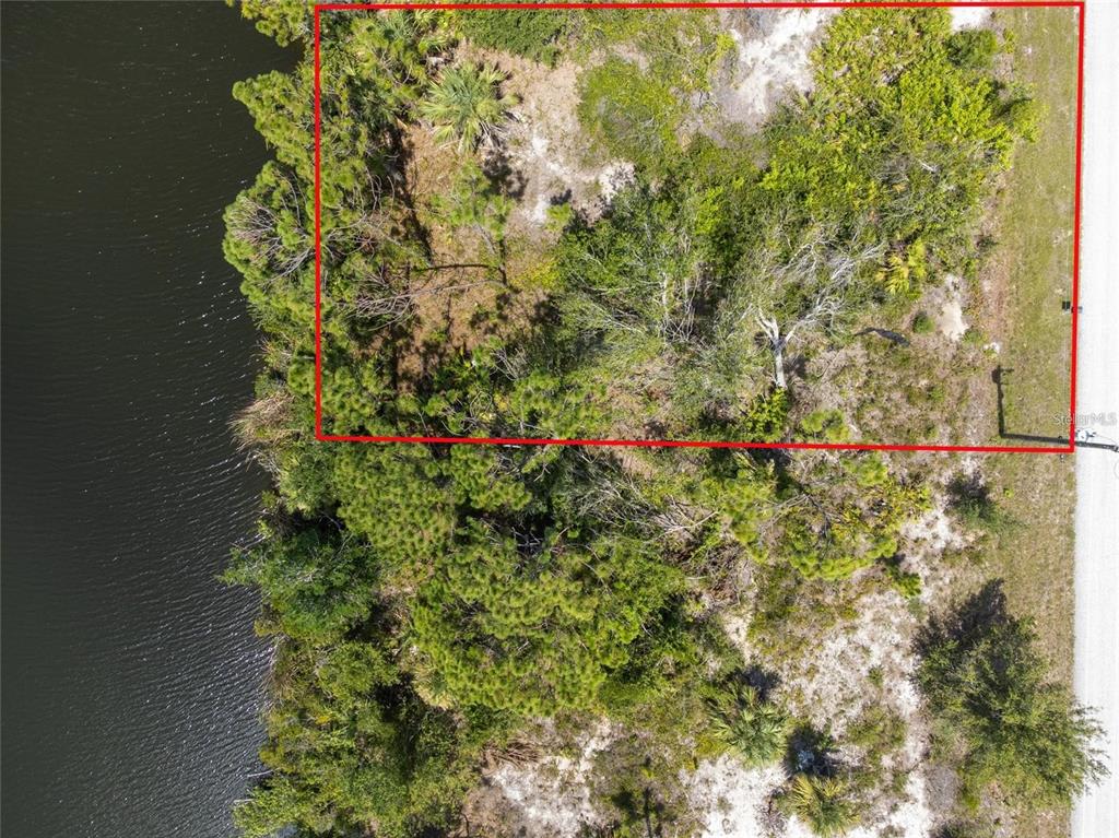 An aerial view shows a vacant, rectangular lot outlined in red bordering a canal — 9602 GAZANIA DRIVE, PORT CHARLOTTE, FL