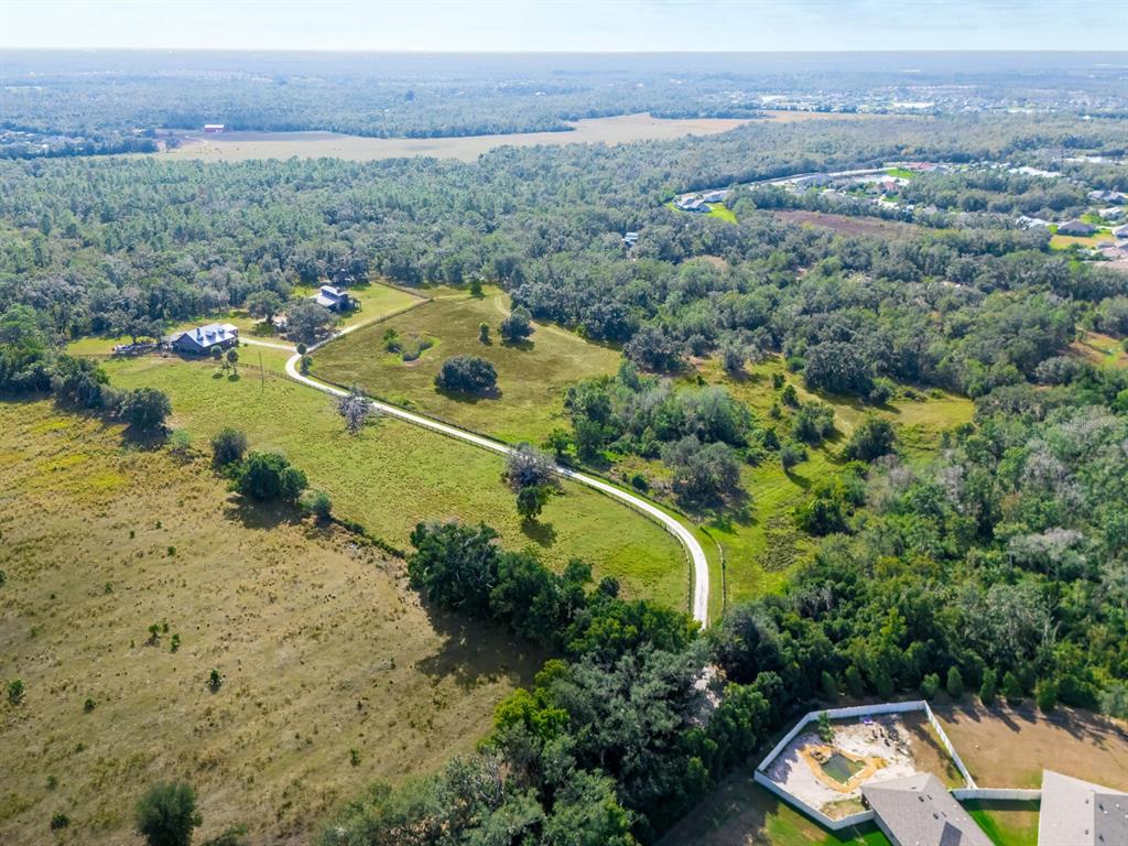 An aerial view shows a winding driveway leading to a house surrounded by large pastures — 2405 N RYE ROAD, PARRISH, FL