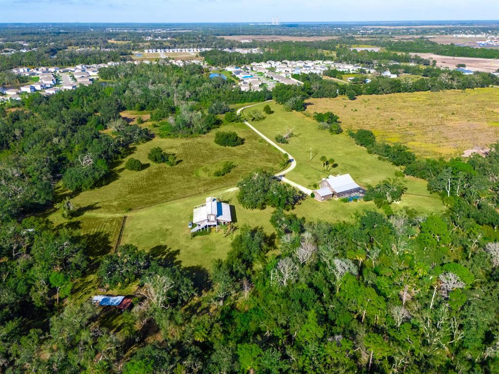 An aerial view shows two houses on a large, grassy lot surrounded by dense trees — 2405 N RYE ROAD, PARRISH, FL