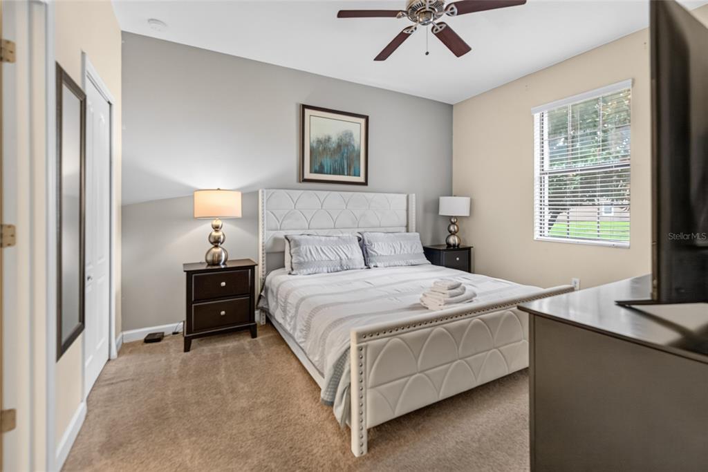 A bedroom features a white tufted bed, two dark nightstands, and a ceiling fan — 1400 WEXFORD WAY, DAVENPORT, FL