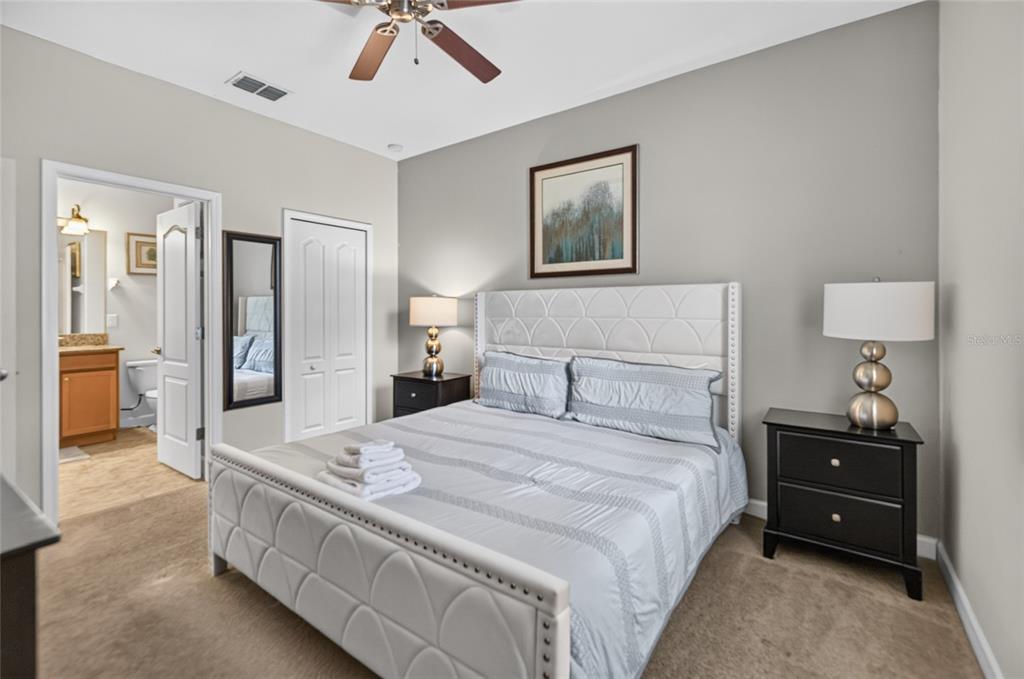 A bedroom features a white tufted bed, two black nightstands, and an attached bathroom — 1400 WEXFORD WAY, DAVENPORT, FL