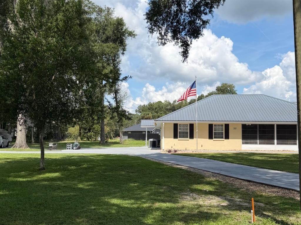 A single-story house with a metal roof and screened porch sits on a grassy lot — 300 SW BRIGHTON COURT, FORT WHITE, FL