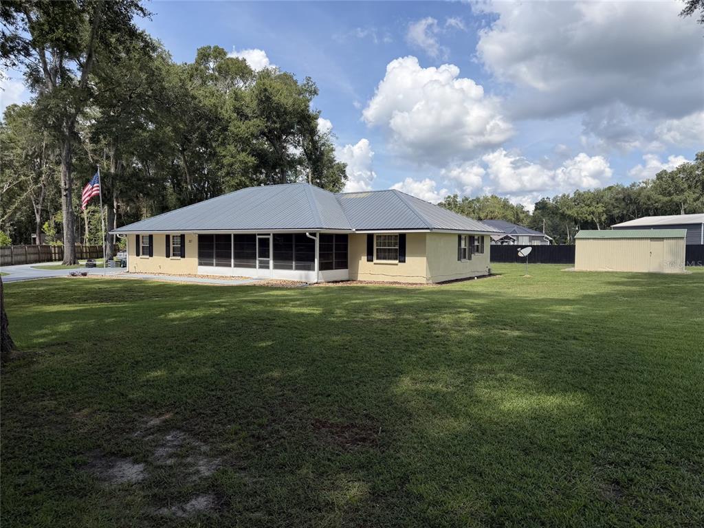 A single-story house with a metal roof, screened porch, and an American flag in front — 300 SW BRIGHTON COURT, FORT WHITE, FL