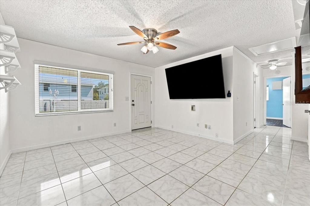 A bright room with white walls, tiled floors, a ceiling fan, and built-in wall shelving — 122 W COLLINS STREET, LAKELAND, FL