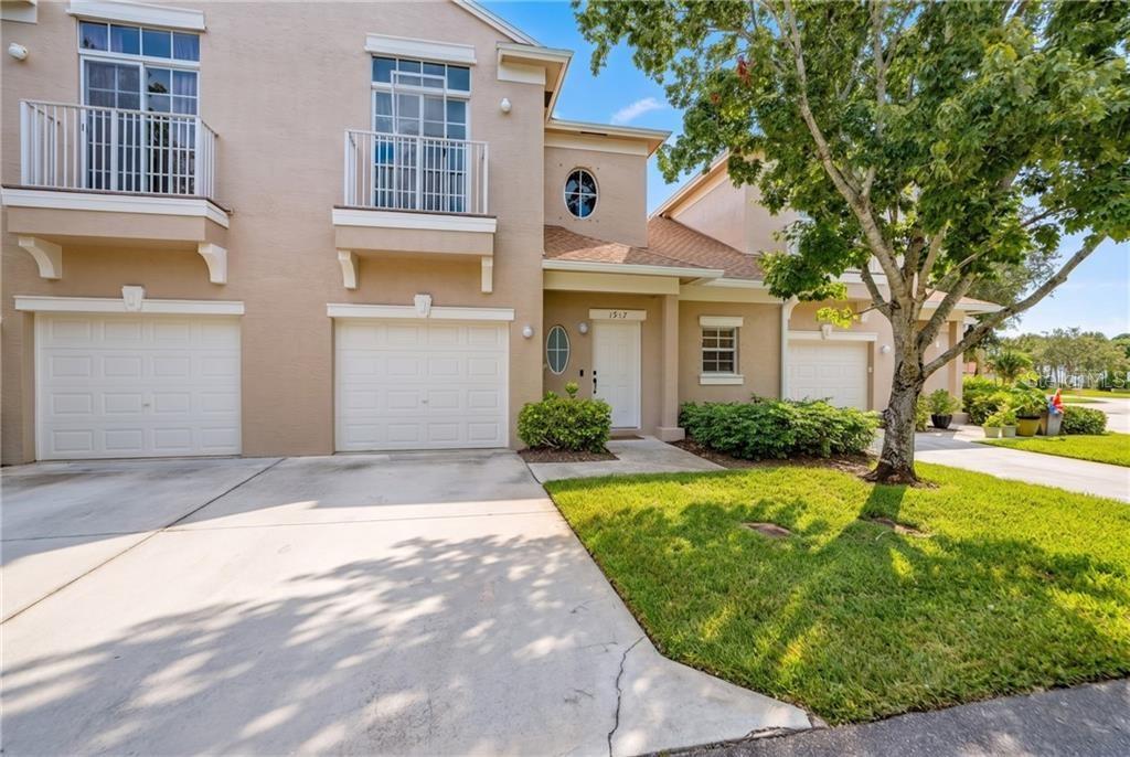 A two-story townhouse with a beige stucco exterior, two garage doors, and a front entrance — 1917 77TH DRIVE, VERO BEACH, FL