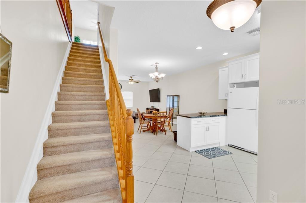 A carpeted staircase leads to an upper level, overlooking a kitchen and dining area — 1917 77TH DRIVE, VERO BEACH, FL