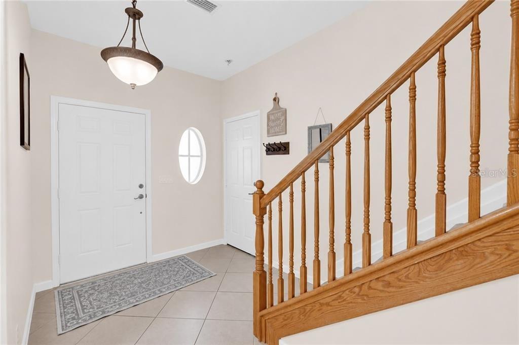 An entryway features a tiled floor, a wooden staircase with railings, and a hanging light fixture — 1917 77TH DRIVE, VERO BEACH, FL