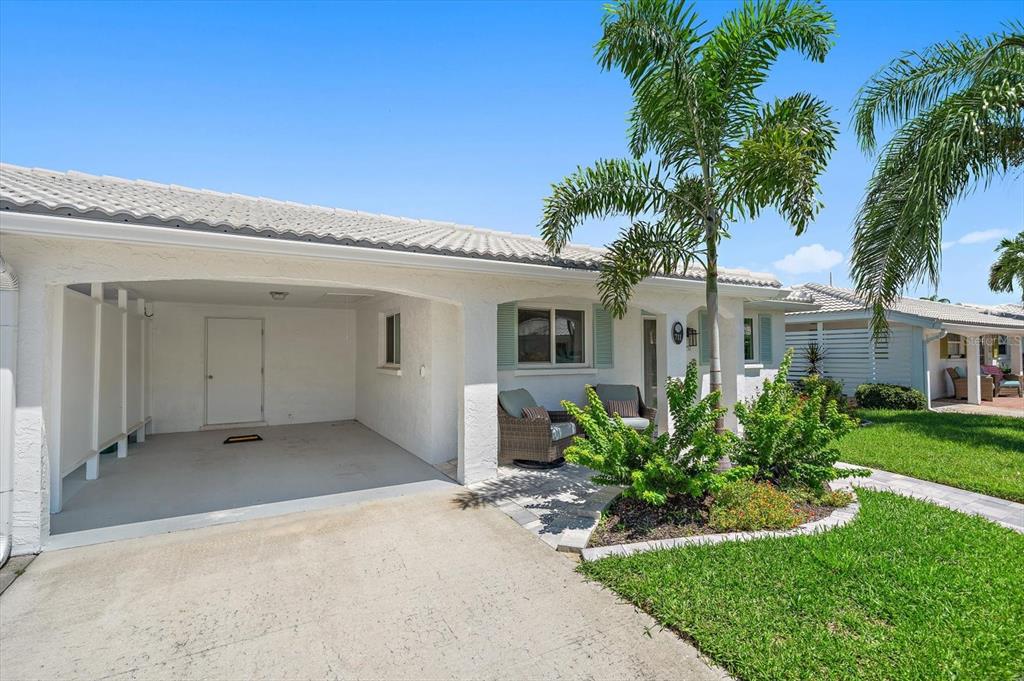 A white house exterior features a covered carport, a small front patio, and a palm tree — 711 SPANISH DRIVE S UNIT 211, LONGBOAT KEY, FL