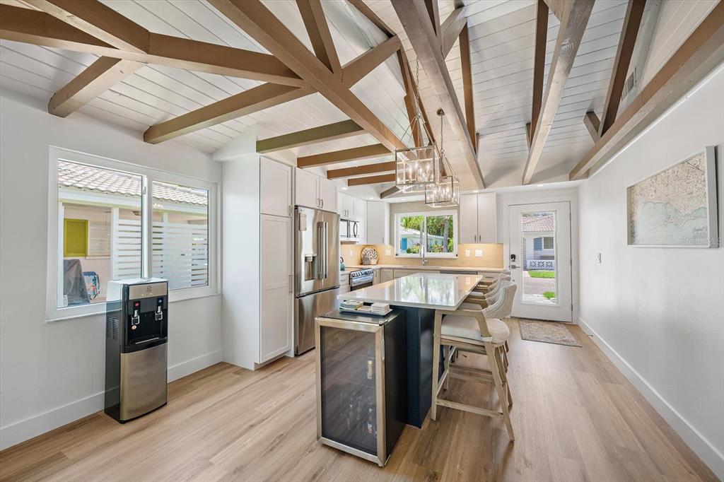 A kitchen with white cabinets, a central island, wood-beamed ceilings, and light wood flooring — 711 SPANISH DRIVE S UNIT 211, LONGBOAT KEY, FL