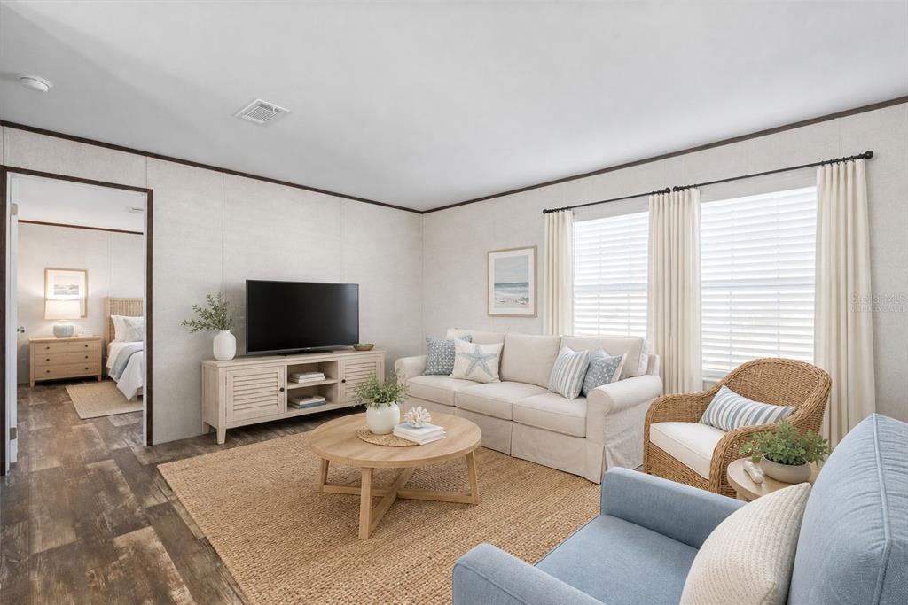 A living room with a beige sofa, wicker chair, blue armchair, and a television console — 224 WOLVERINE AVENUE, NORTH PORT, FL
