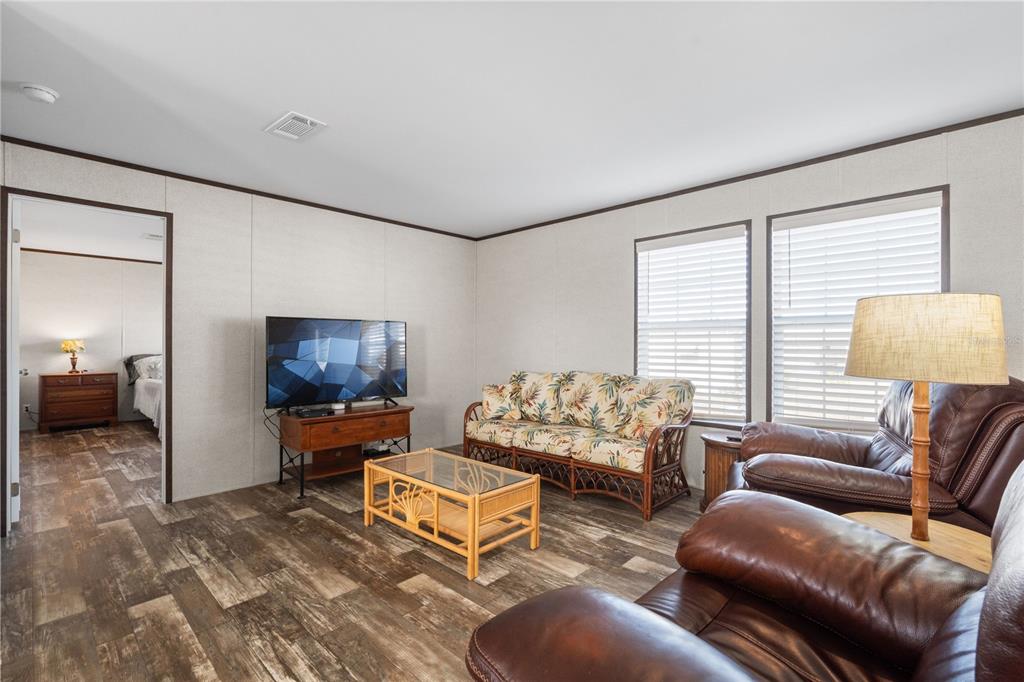 A living room features wood-look flooring, a floral sofa, leather recliners, and a television stand — 224 WOLVERINE AVENUE, NORTH PORT, FL
