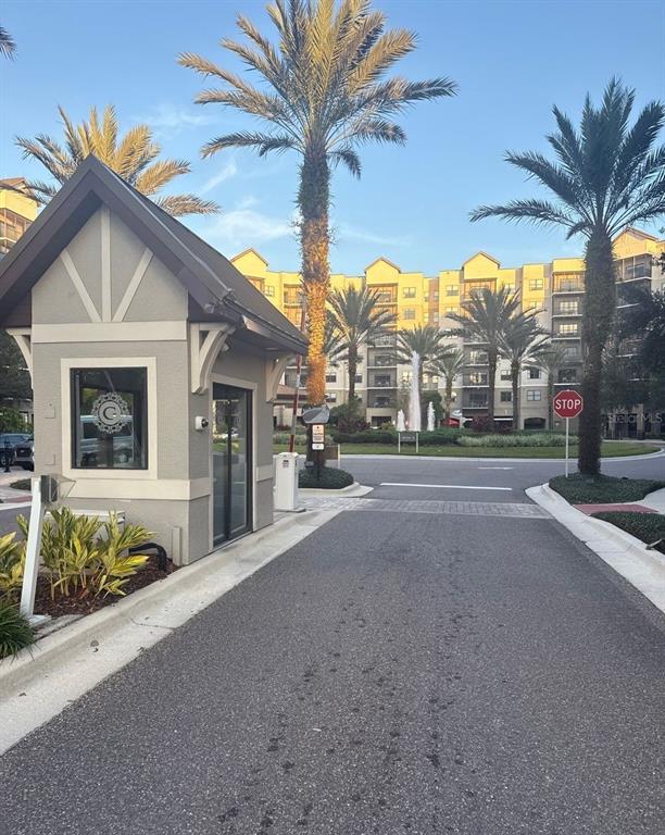 A gated entrance with a guardhouse, palm trees, and a multi-story apartment building in background — 14501 GROVE RESORT AVENUE UNIT 2604, WINTER GARDEN, FL