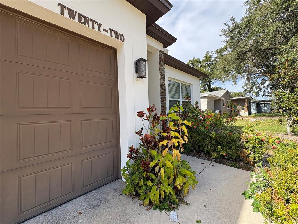 A tan garage door sits beside a landscaped walkway and a house with stucco siding — 22 DEACON JONES BOULEVARD, ORLANDO, FL