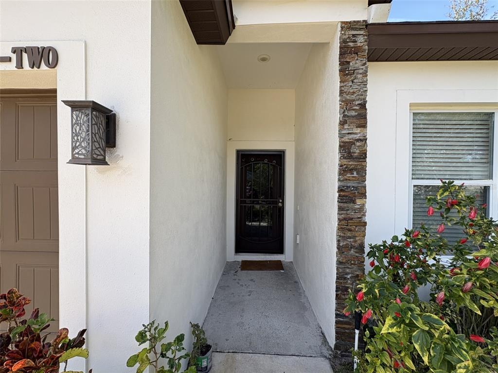 A concrete walkway leads to a recessed front door with a dark metal security screen — 22 DEACON JONES BOULEVARD, ORLANDO, FL