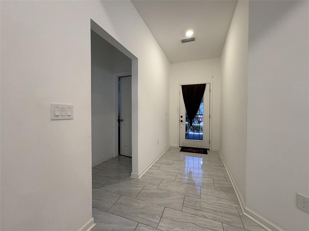 A bright entryway features light gray tile flooring, white walls, and a glass-paneled front door — 22 DEACON JONES BOULEVARD, ORLANDO, FL