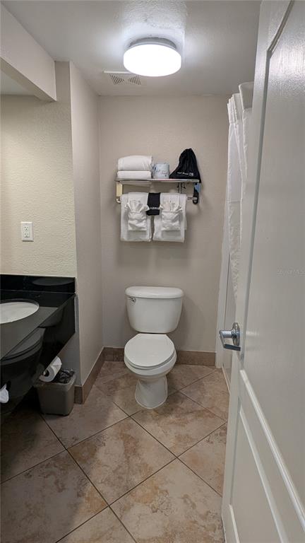 A bathroom features a toilet, a vanity with a black countertop, and a towel shelf — 3000 MAINGATE LANE UNIT 421, KISSIMMEE, FL