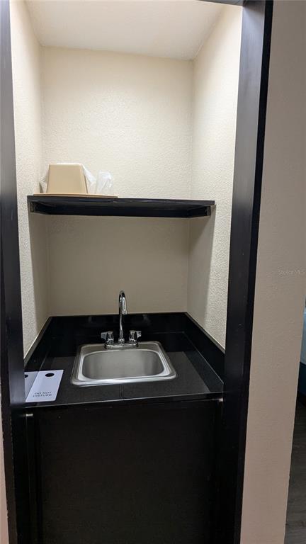 A small wet bar area features a stainless steel sink, black countertop, and overhead shelf — 3000 MAINGATE LANE UNIT 421, KISSIMMEE, FL