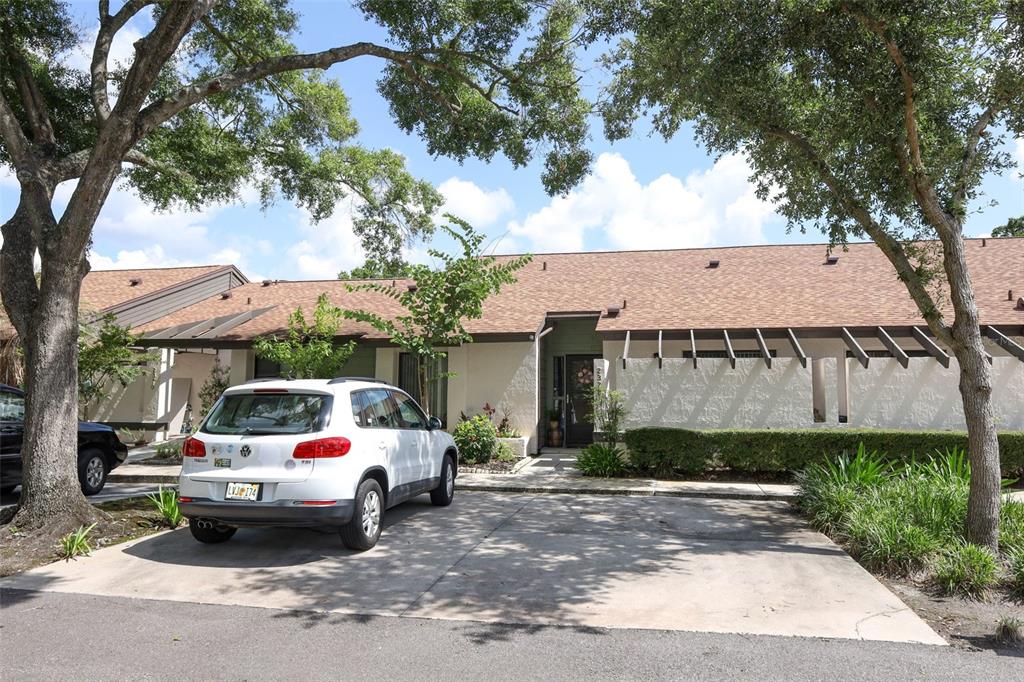 A white SUV is parked in the driveway of a single-story home with brown shingles — 2372 SUN VALLEY CIRCLE UNIT 2372, WINTER PARK, FL