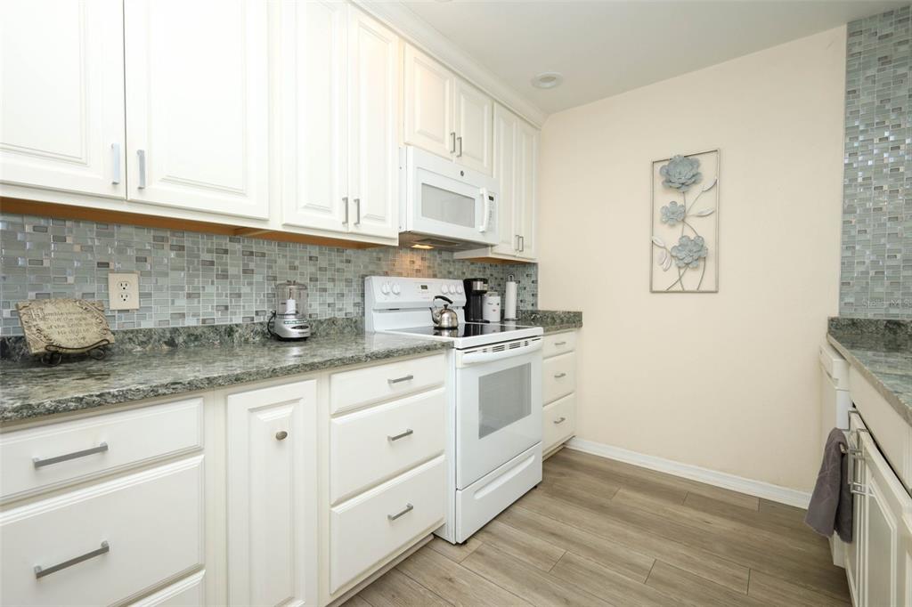 A kitchen with white cabinets, a white stove, a tiled backsplash, and granite countertops — 2372 SUN VALLEY CIRCLE UNIT 2372, WINTER PARK, FL