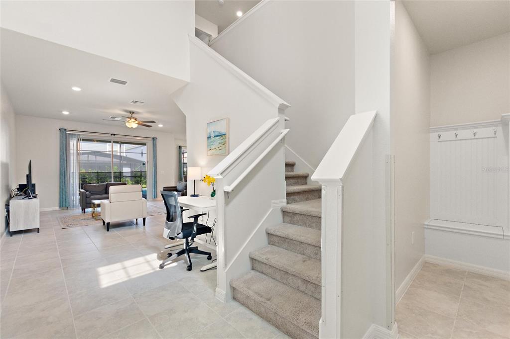 An interior view shows a staircase, a small desk area, and a living room beyond — 7384 OAKMOSS LOOP, DAVENPORT, FL