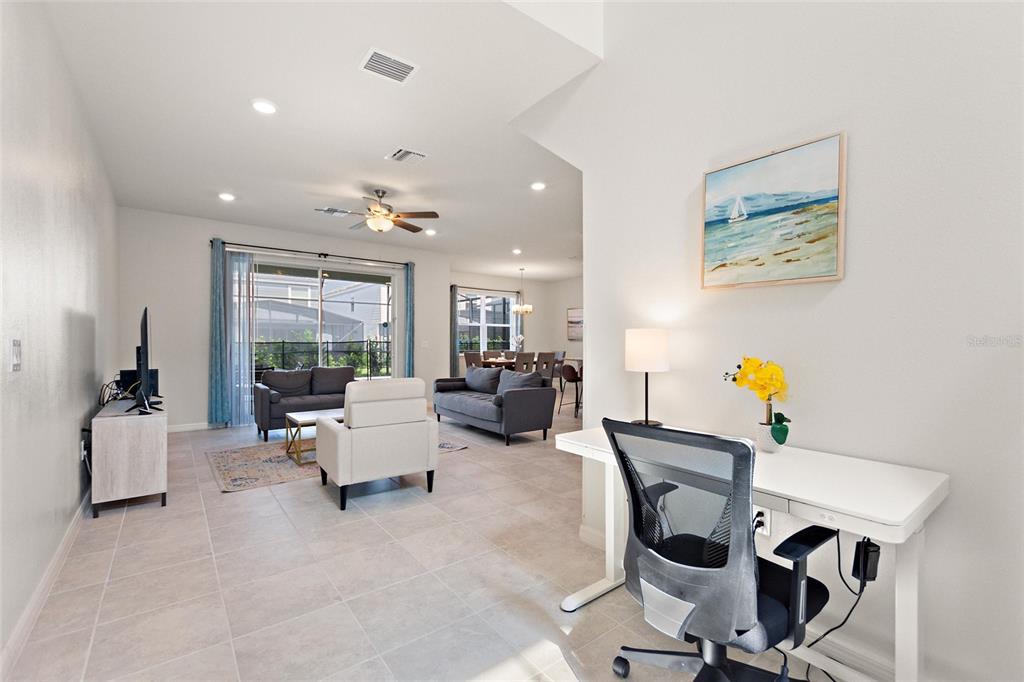 A bright open-concept living area features a desk in the foreground and a dining space — 7384 OAKMOSS LOOP, DAVENPORT, FL