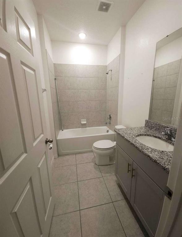 A kitchen features light-colored cabinets, granite countertops, stainless steel appliances, and a gray island — 522 FELTRIM MANOR ROAD, HAINES CITY, FL