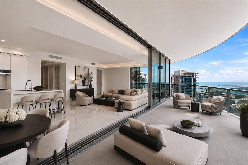 A bright, open-concept living area with floor-to-ceiling windows, white tile floors, and a modern kitchen — 400 CENTRAL AVENUE UNIT 2901, ST PETERSBURG, FL